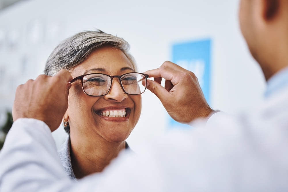 An optician helping a smiling client with prescription glasses