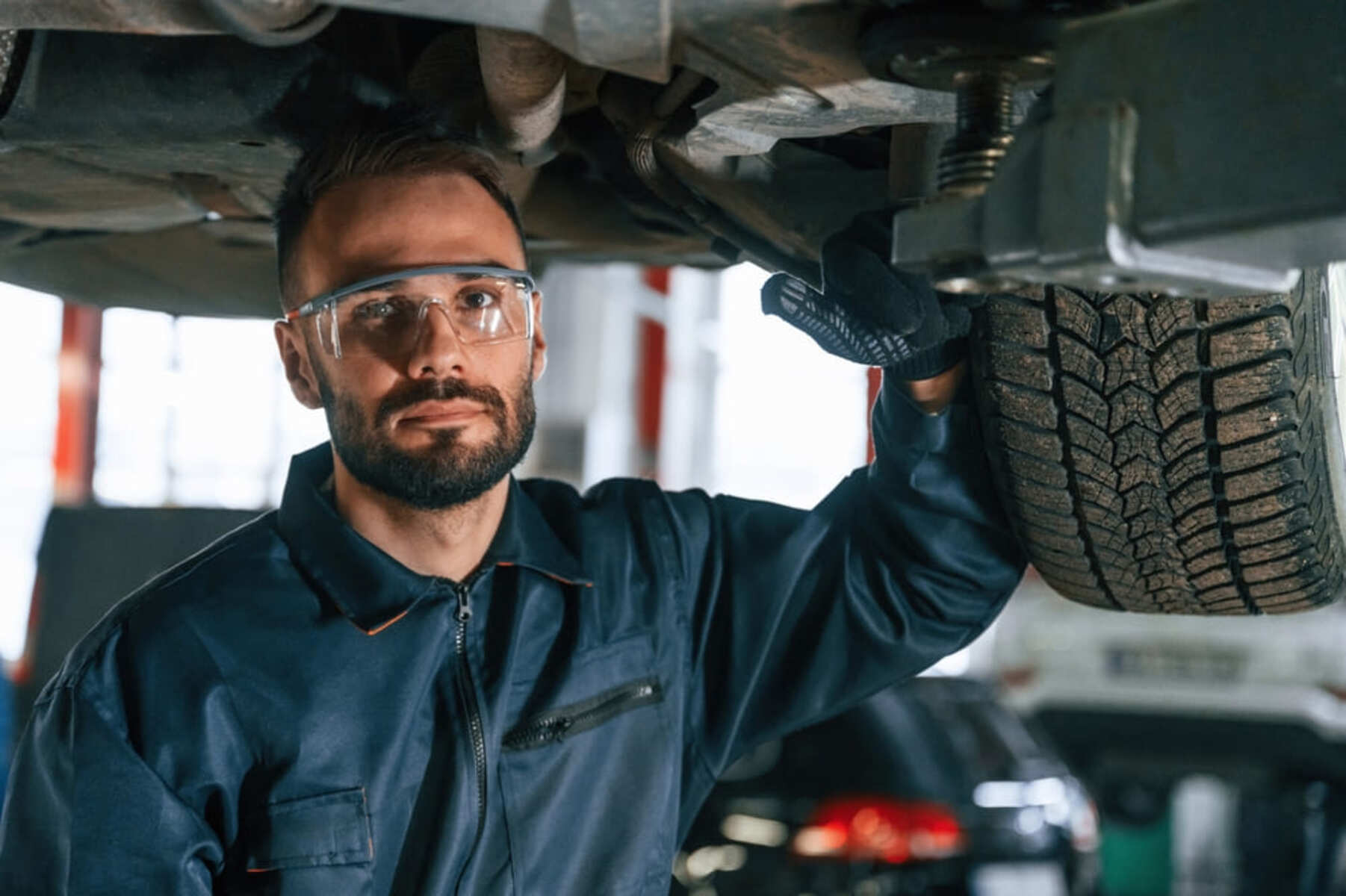 ok.vision impact resistant lenses A mechanic wearing impact resistant lenses on his safety glasses inspects the underside of a car.