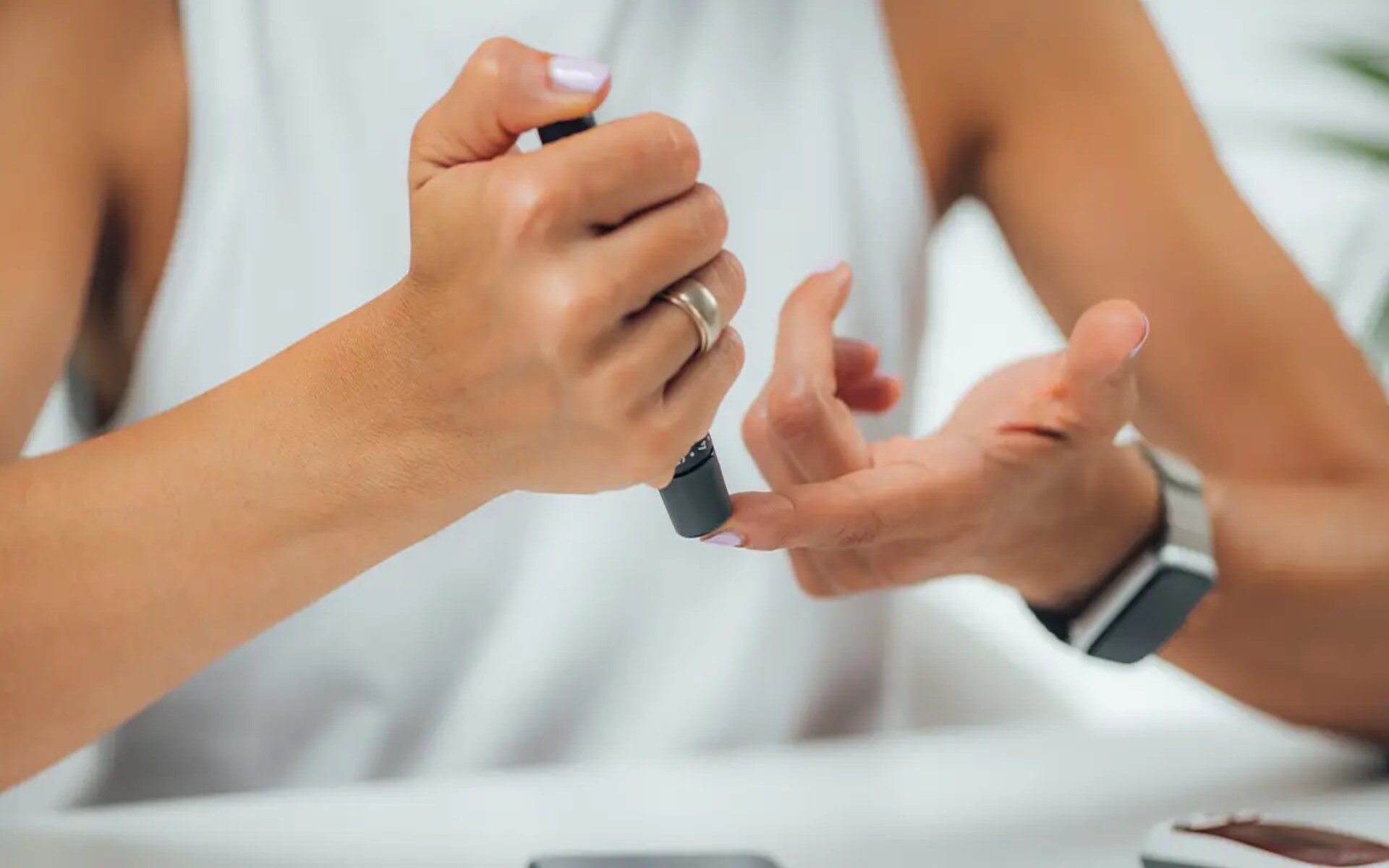 A person with diabetes in the workplace checking their blood sugar level using a lancet device.
