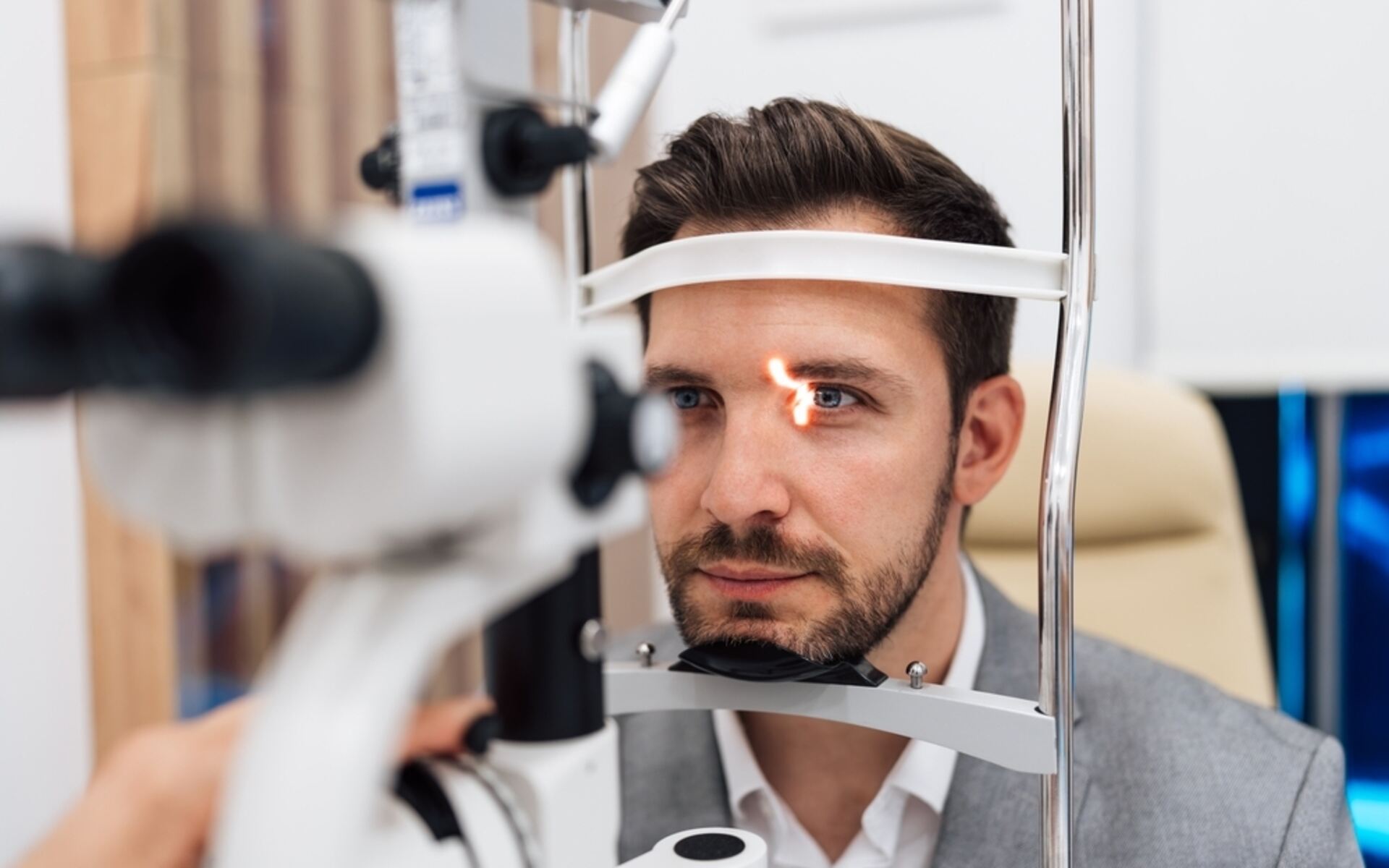 VCD annual eye health exam A man undergoing an annual eye health exam with a slit lamp at an optometrist’s office.