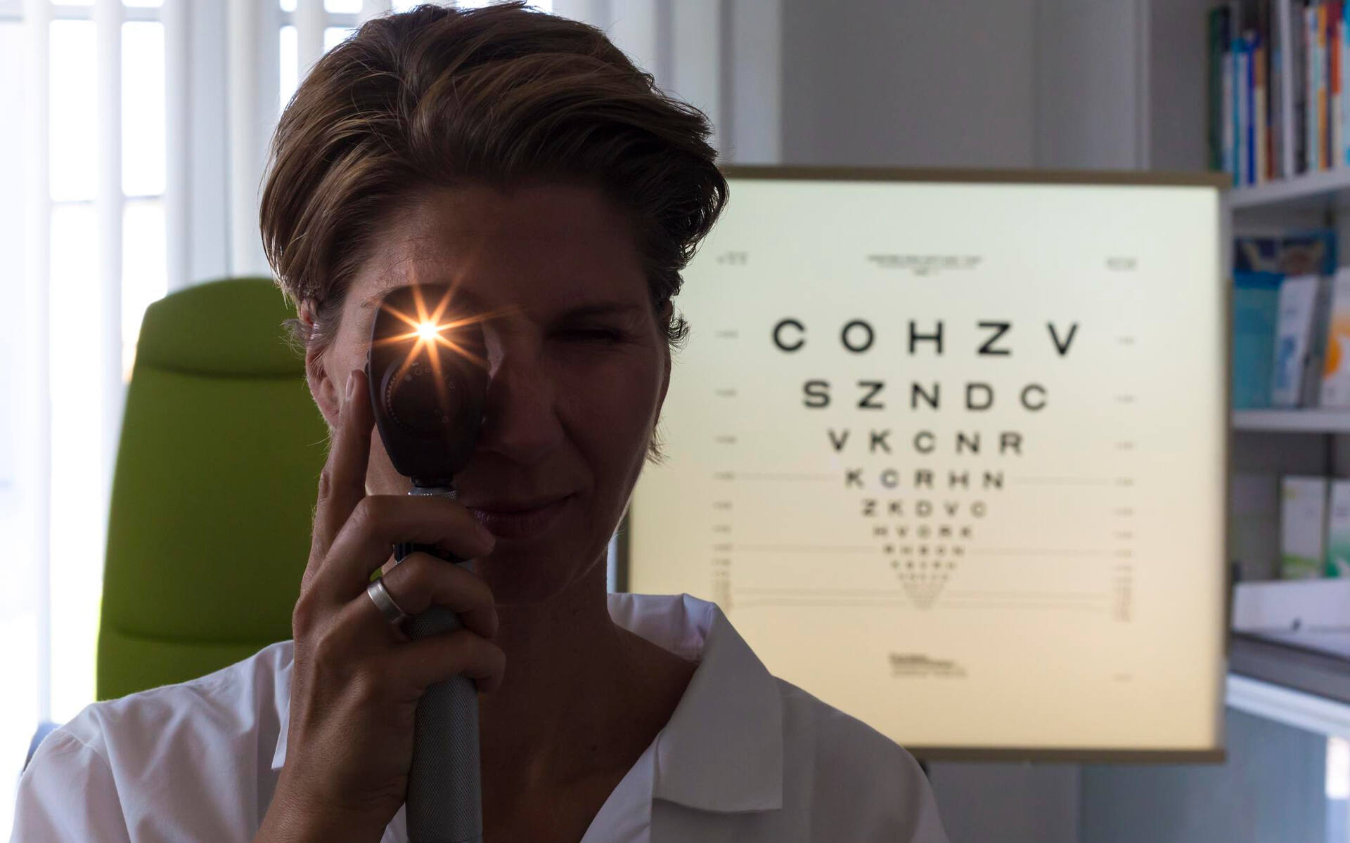 VCD eye pain An eye care professional uses an ophthalmoscope to examine a patient, a key step in diagnosing causes of eye pain.